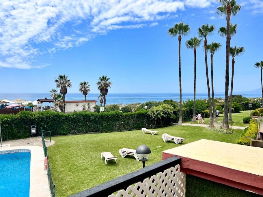 uma vista para um quintal com uma piscina e palmeiras em OleHolidays 1113 Romana Playa vistas al mar em Marbella