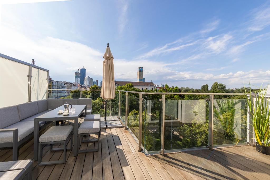 a balcony with a table and an umbrella at SkyLine Apartment mit Terrasse close to Lakes in Vienna