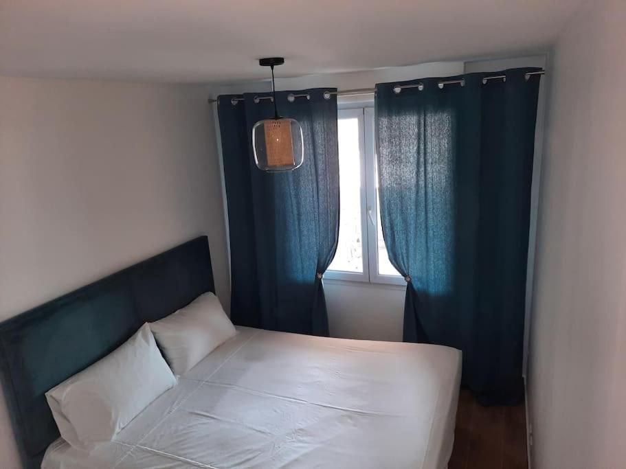 カンヌにあるCosy Appartementのベッドルーム1室(青いカーテン、窓付)