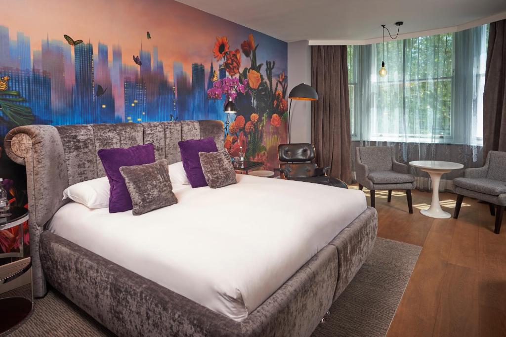 a bedroom with a large bed with purple pillows at Malmaison London in London
