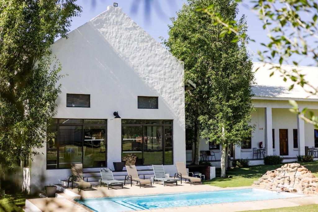 a white house with a swimming pool in front of it at Monte Bello Estate, Cork Tree Collection in Bloemfontein