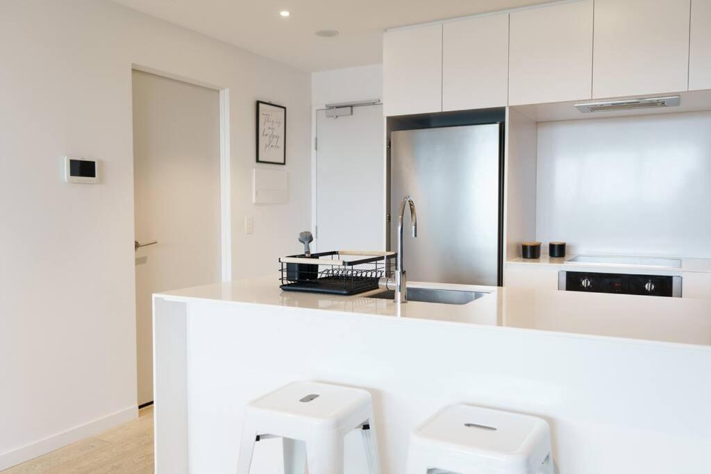 a kitchen with white cabinets and white stools at Modern 1 Bed Opposite Racecourse in Melbourne
