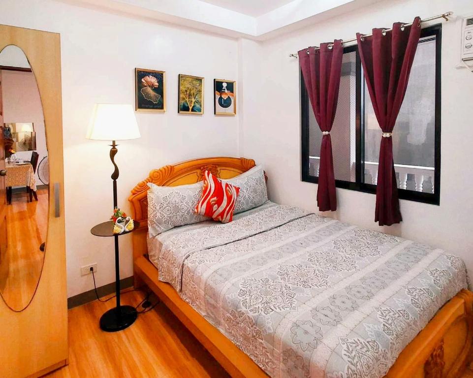 1 dormitorio con 1 cama con cortinas rojas en Retreat to a Stylish Flat w/ Balcony + Garden View en Liloan