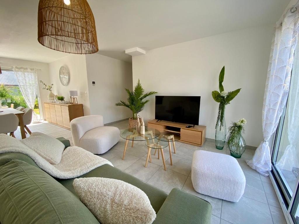 a living room with a green couch and a tv at Les Voiles Blanches - Accès plage & centrale - Calme et Tranquillité in Brétigny