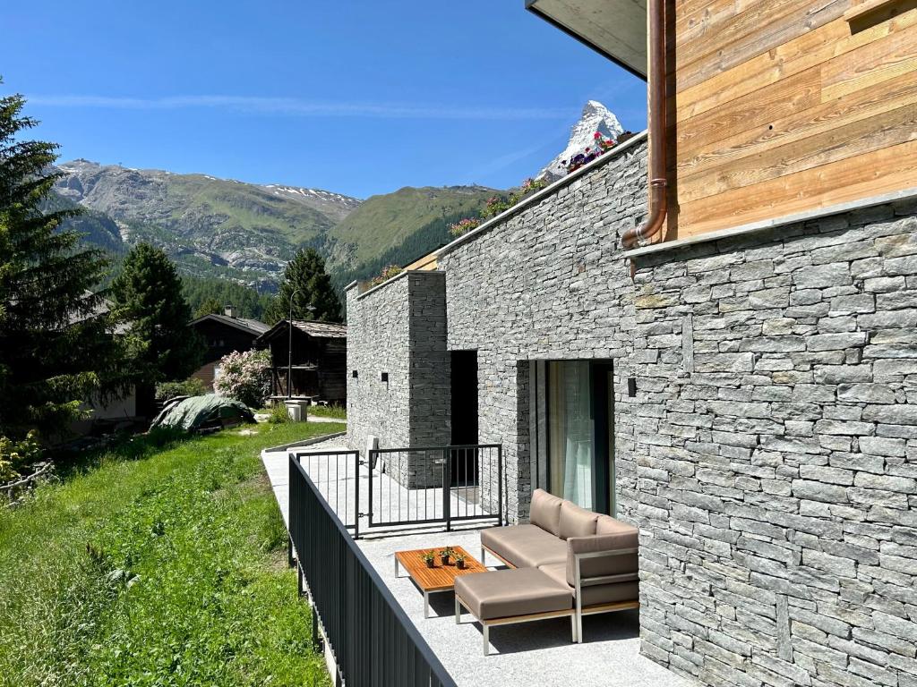 ein Steinhaus mit einem Sofa auf dem Balkon in der Unterkunft Chalet Coral und Zermatter Stadel in Zermatt