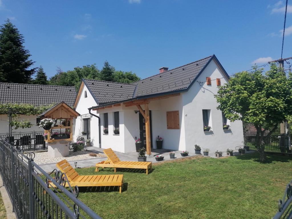 ein weißes Haus mit Bänken im Hof in der Unterkunft Őrségi Éden Vendégház in Hegyhátszentjakab