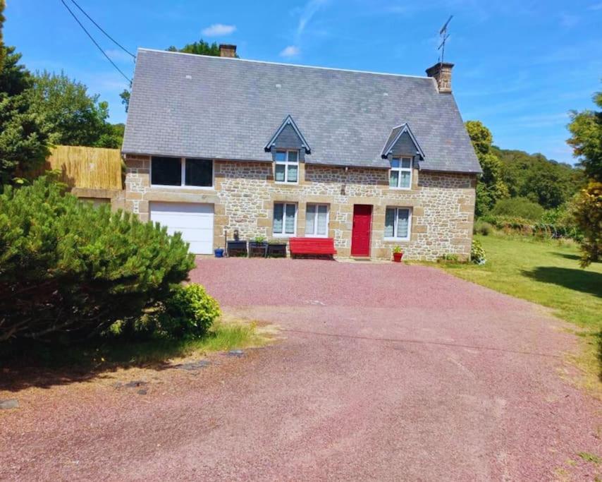a brick house with a red door and a driveway at Maison en pierre au milieu du bocage in Coulouvray-Boisbenâtre