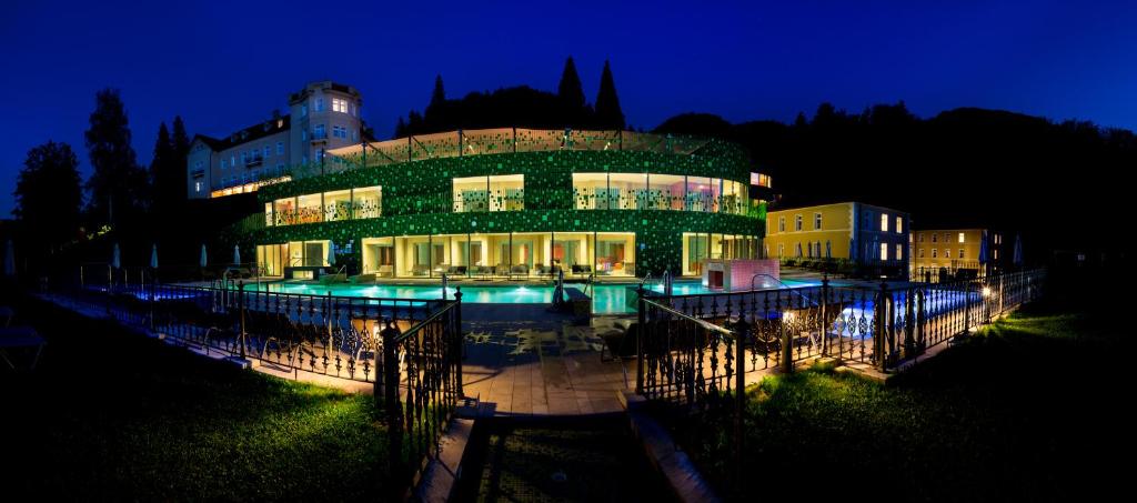 un edificio con una piscina delante de él por la noche en Rimske Terme Resort - Hotel Rimski dvor, en Rimske Toplice
