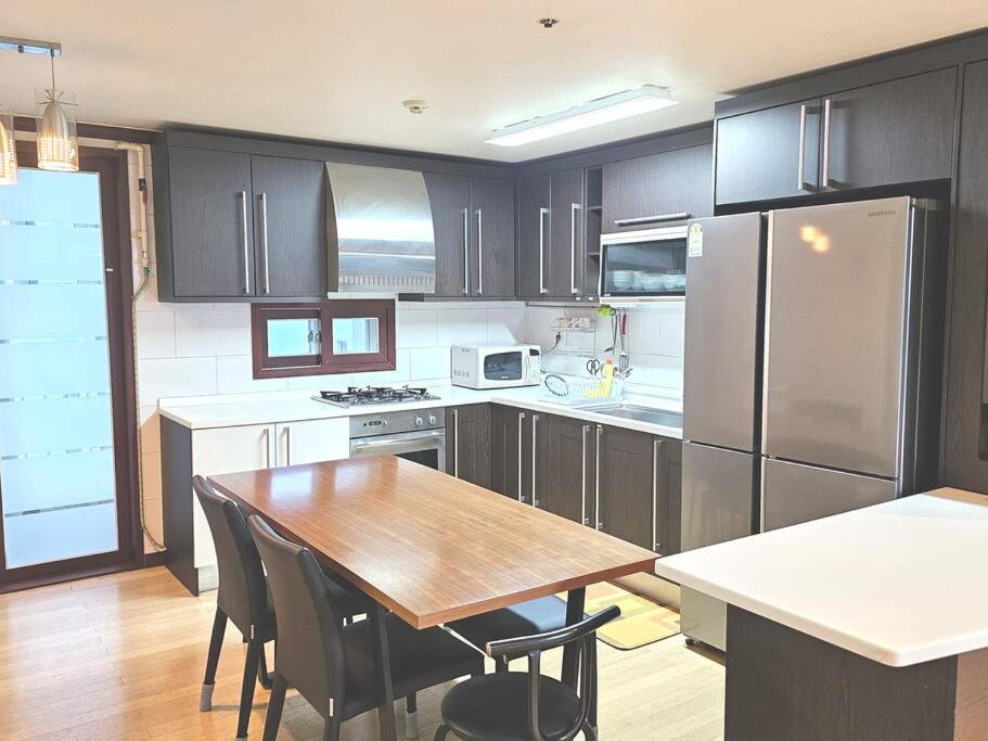 a kitchen with a wooden table and a refrigerator at Dongtan Sharp-2 Family House in Hwaseong