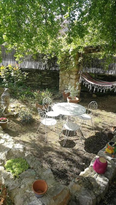 a patio with a table and chairs in a garden at Maison a Rustrel (A coté du Colorado Provençal ) in Rustrel