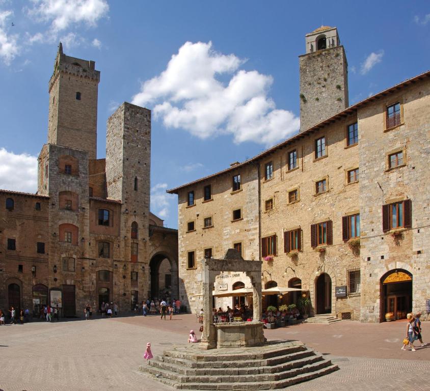un grand bâtiment avec deux tours dans une cour dans l'établissement Leon Bianco, à San Gimignano