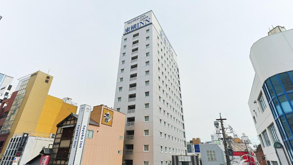 a tall building in the middle of a city at Toyoko Inn Kintetsu Yokkaichi eki Kita guchi in Yokkaichi