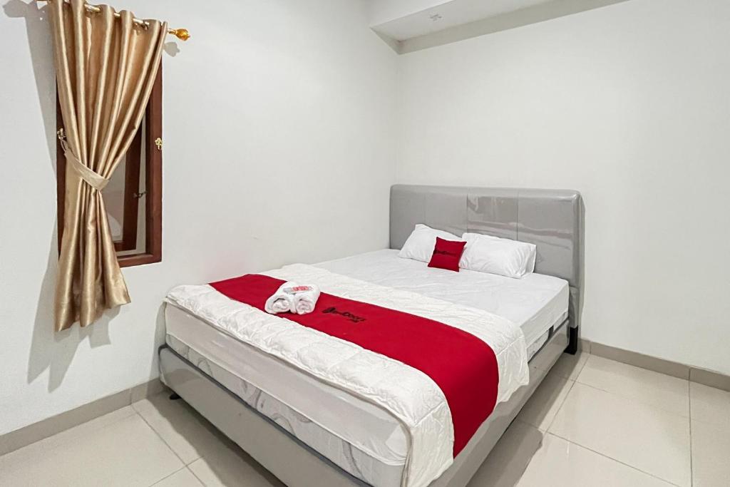 a bedroom with a bed with a red and white blanket at RedDoorz @ Kali Balok Lampung in Geruntang