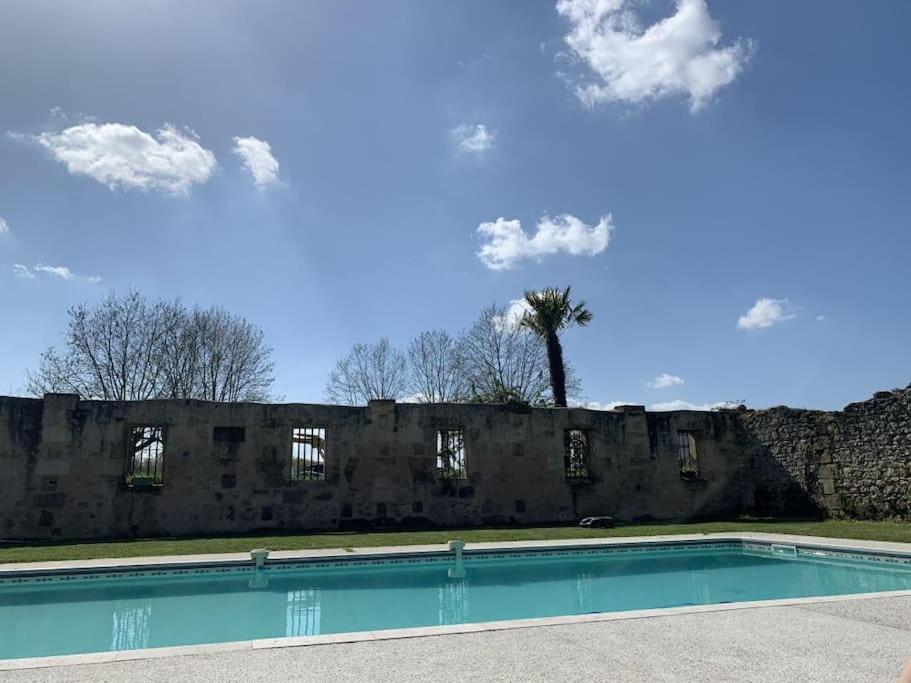 - une piscine en face d'un mur en pierre dans l'établissement Le Canteloup, à Saint-Caprais-de-Bordeaux