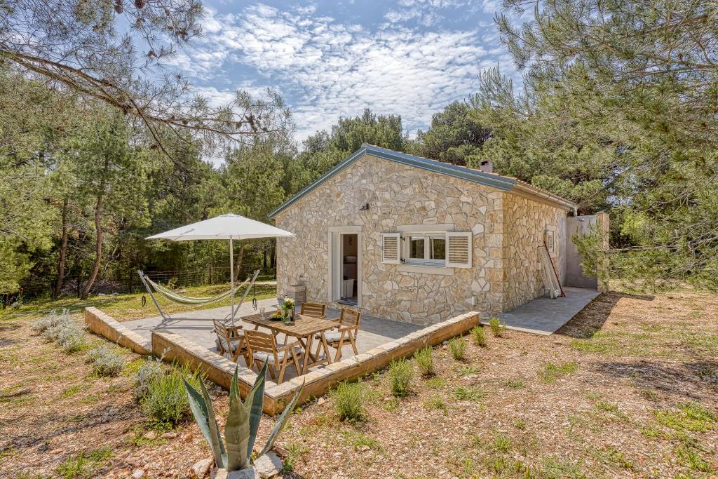 um chalé de pedra com uma mesa e um guarda-chuva em Eco House Casa Grigia - Happy Rentals em Čunski