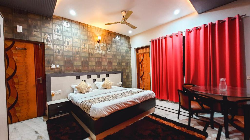 a bedroom with a bed and a table and red curtains at Hotel Rajyashree Palace in Varanasi