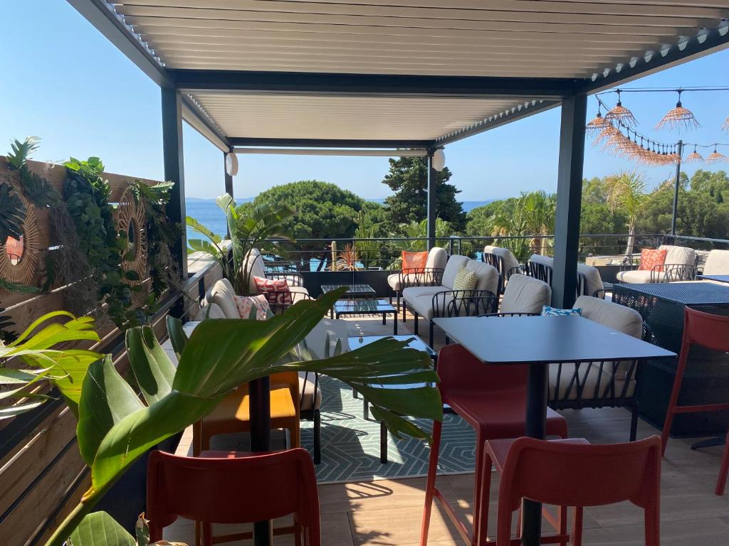 a patio with tables and chairs and a view of the ocean at Les Alcyons in Le Lavandou