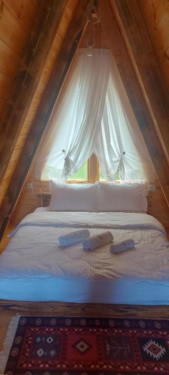 a bedroom with a bed with white sheets and a window at Camping Farm Shelegur in Leskovik