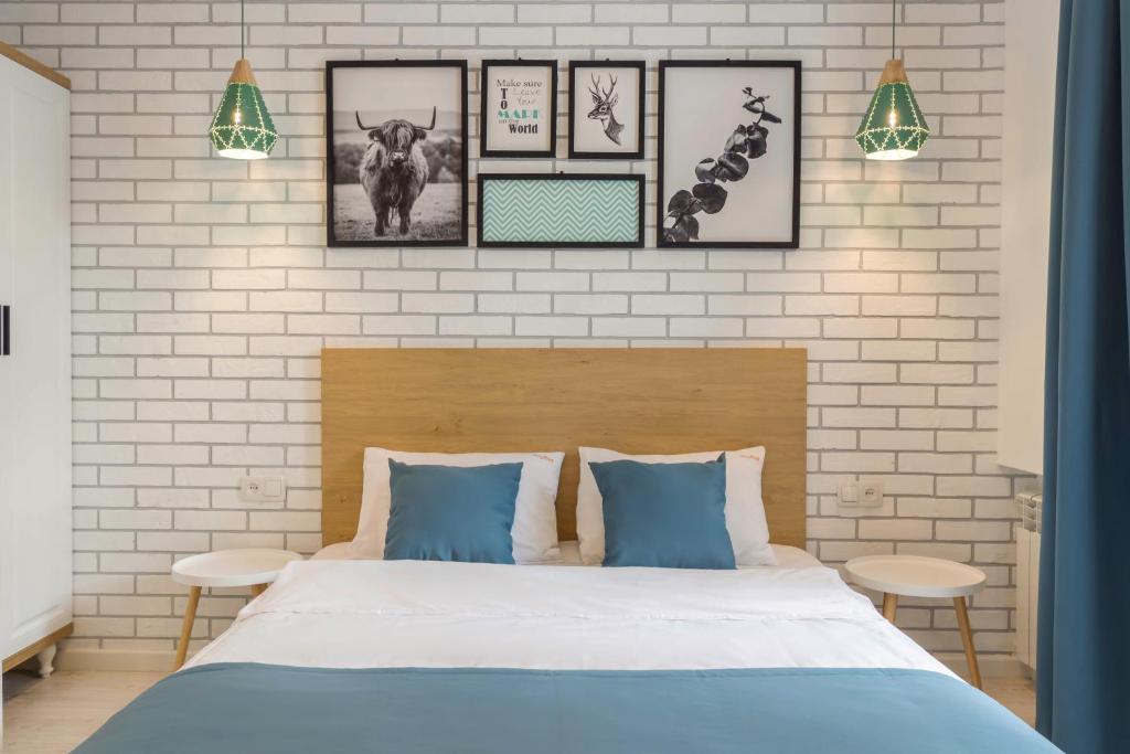 a bedroom with a bed with blue pillows and pictures on the wall at Idea Design Apart-Hotel in Kyiv