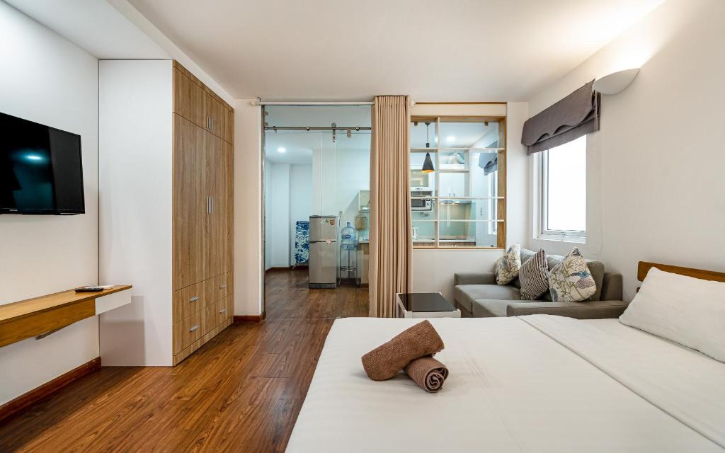 ein Schlafzimmer mit einem Bett, einem TV und einem Sofa in der Unterkunft SaigonOne Serviced Apartment in Ho-Chi-Minh-Stadt