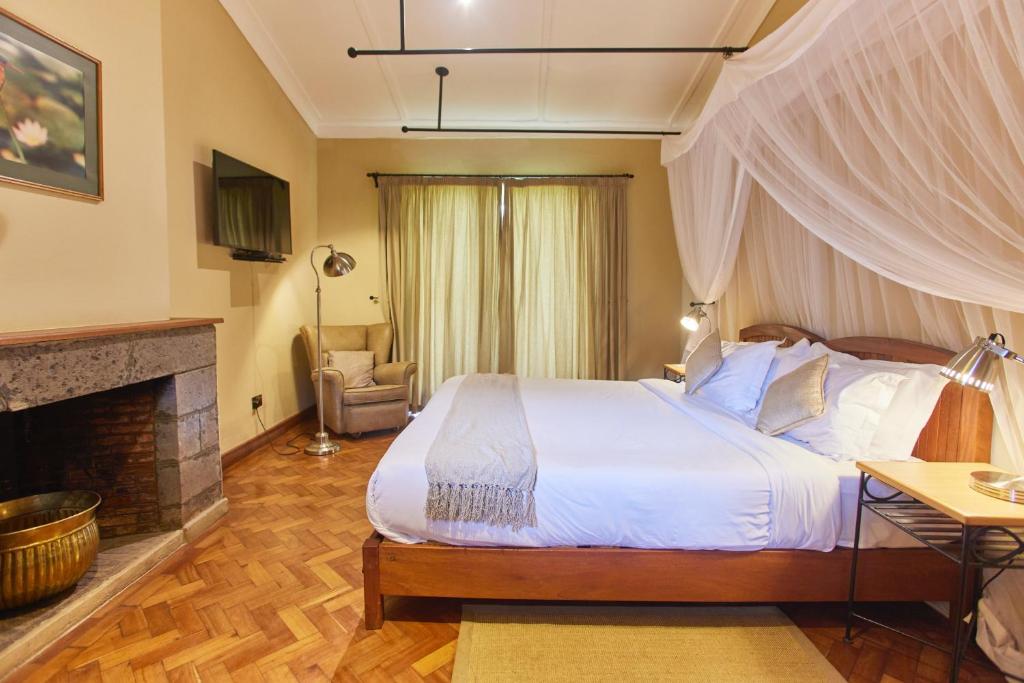 a bedroom with a large bed and a fireplace at Aero Club of East Africa in Nairobi