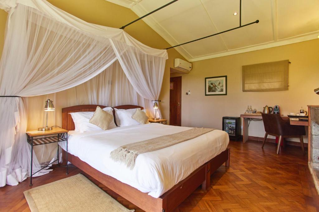 a bedroom with a bed with white curtains and a desk at Aero Club of East Africa in Nairobi