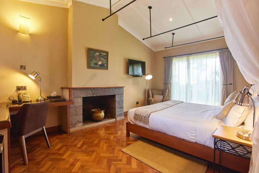 a bedroom with a bed and a desk and a fireplace at Aero Club of East Africa in Nairobi