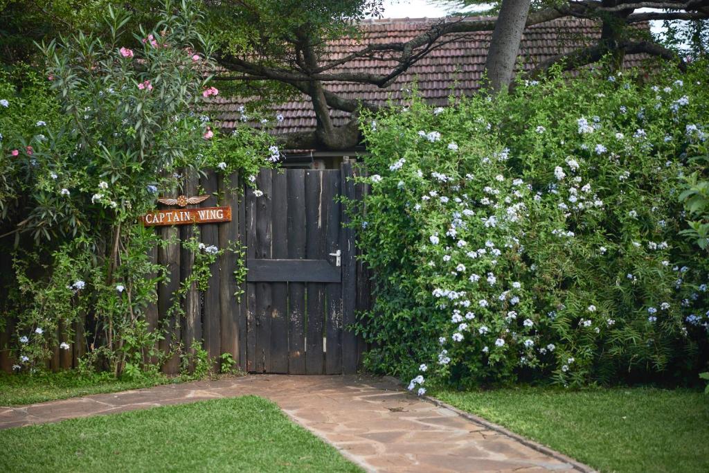 a wooden gate in a garden with white flowers at Aero Club of East Africa in Nairobi