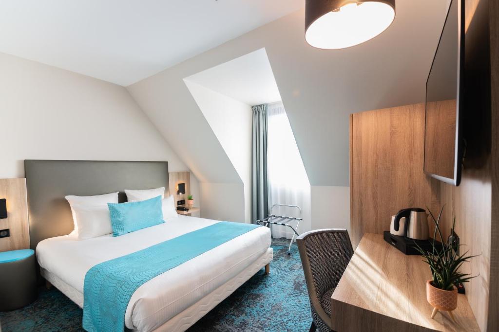 a bedroom with a king sized bed and a desk at Hôtel Turenne in Colmar