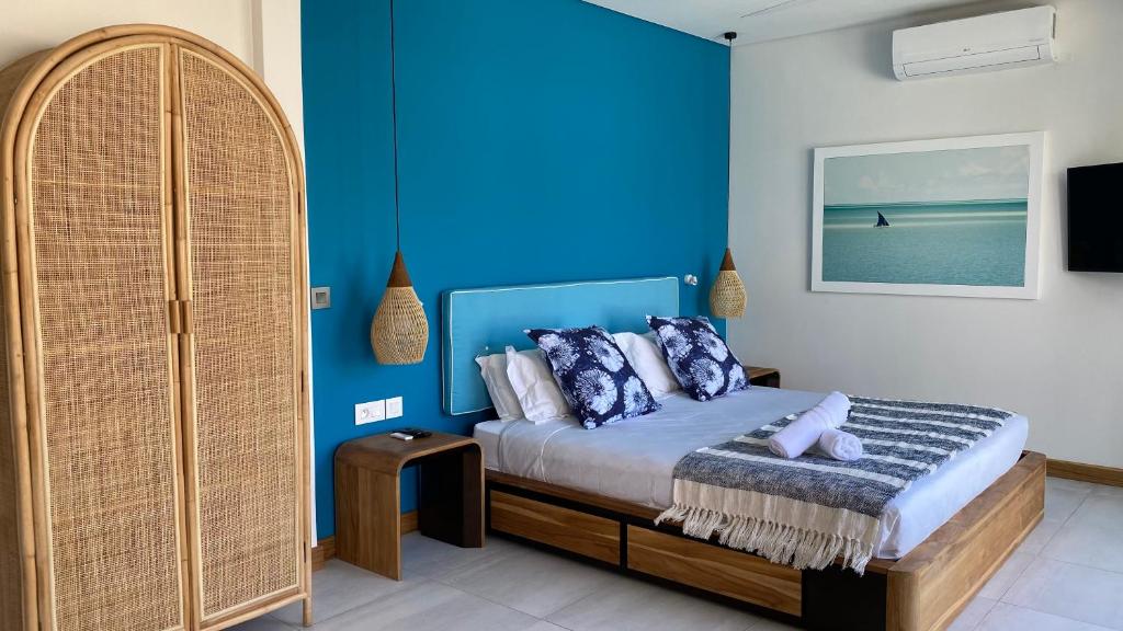 - une chambre avec un lit et un mur bleu dans l'établissement Blue Ocean Suites & Apartments, à Trou dʼ Eau Douce