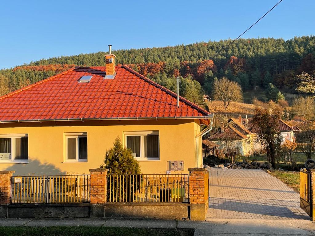 una casa amarilla con techo rojo y valla en Kristóf Vendégház en Bükkszék