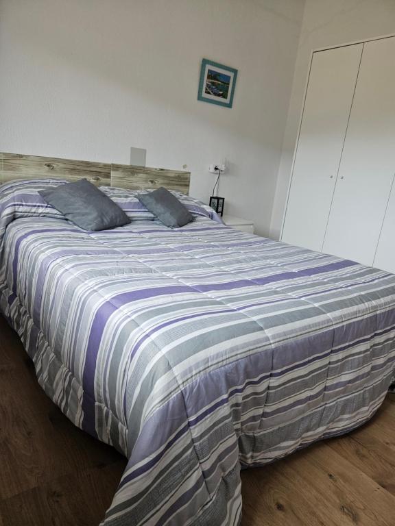 a large bed with a striped comforter in a bedroom at Apartamento rural in Pravia