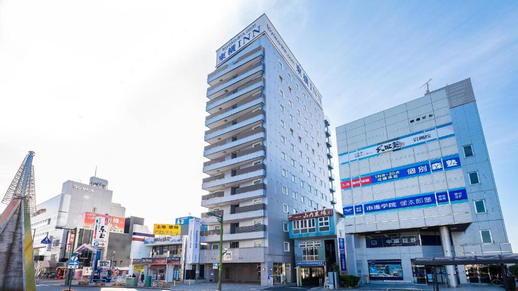un edificio alto en medio de una ciudad en Toyoko Inn Saitama Iwatsuki Ekimae, en Saitama