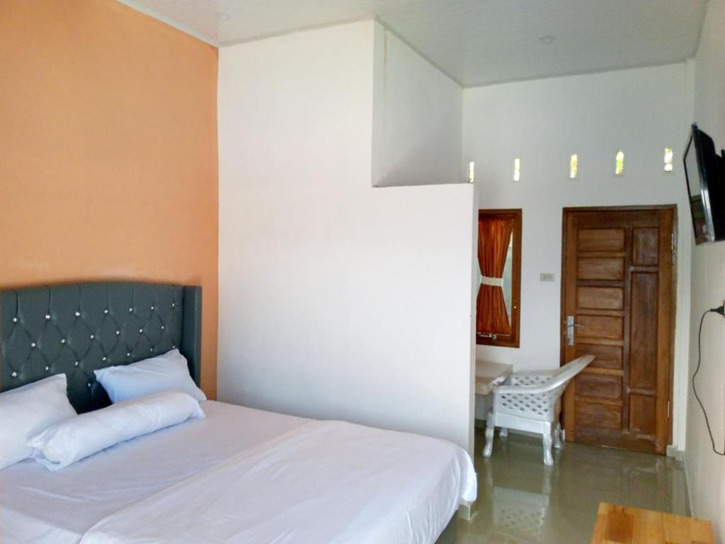 a bedroom with a bed and a table and a chair at RedDoorz @ Sihole Paradise Inn Parbaba in Sinapuran