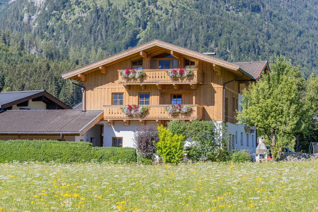 ein Haus mit Blumen auf dem Balkon auf einem Feld in der Unterkunft Ferienhaus Hohenwarter in Lofer