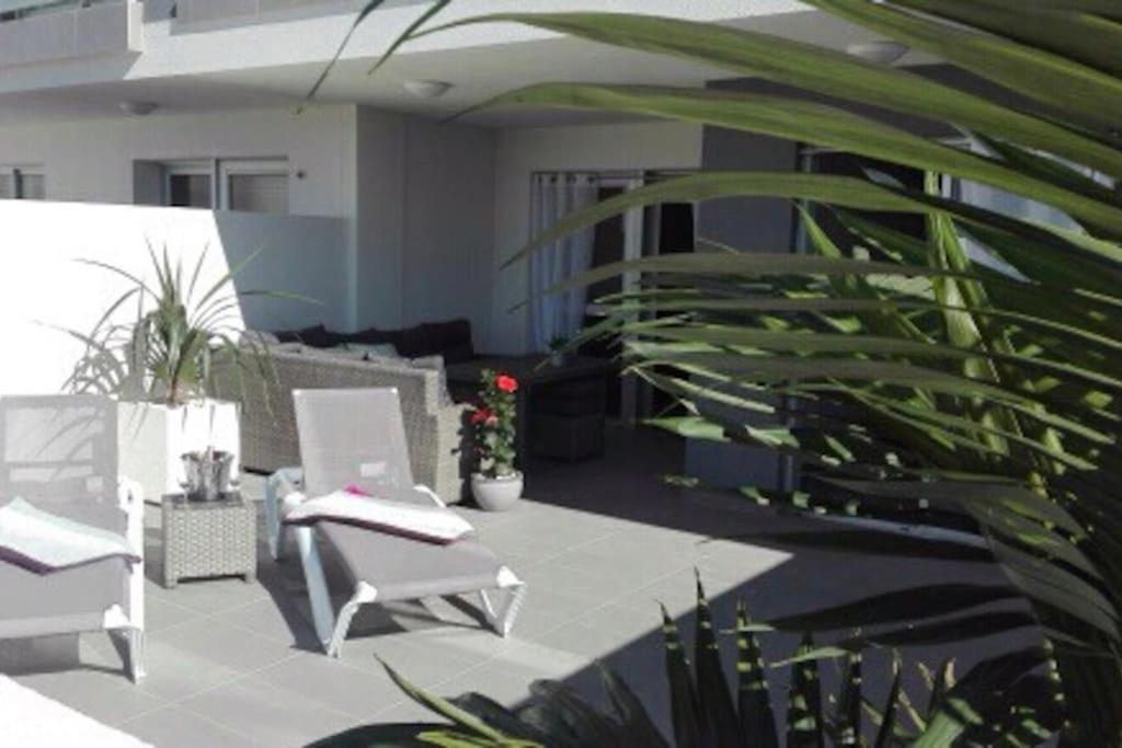 a patio with two white chairs and plants at First Class Holiday Tejita WiFiber in Granadilla de Abona