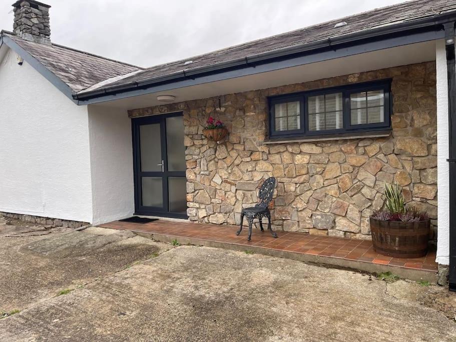 a stone house with a bench in front of it at Spacious 1 bed bungalow located on a Gower Sheep Farm in Swansea