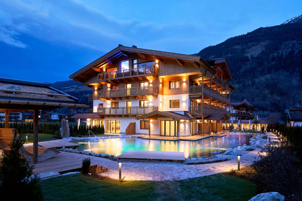 a house with a swimming pool in front of a building at Hotel Wöscherhof - 4 Sterne Superior in Uderns