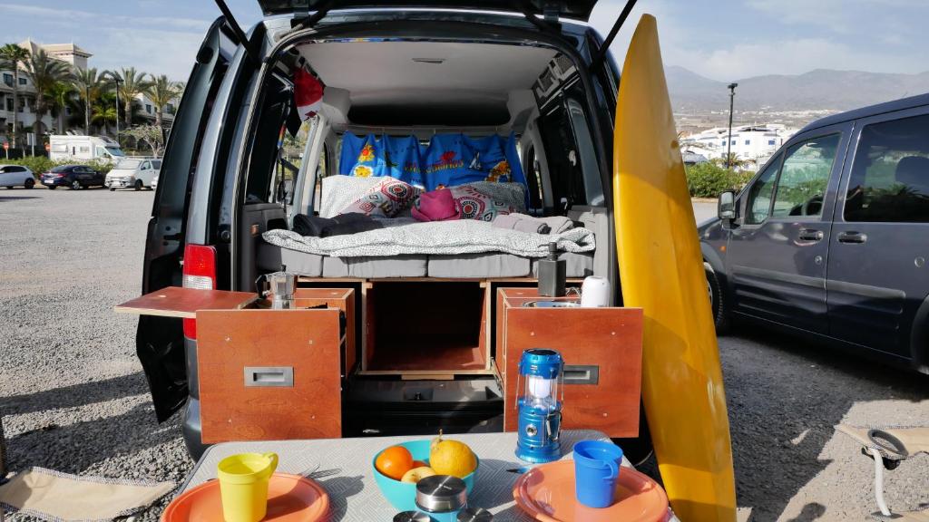 uma carrinha com a porta aberta com uma cama e uma prancha de surf em EndlessCamperVan em San Miguel de Abona