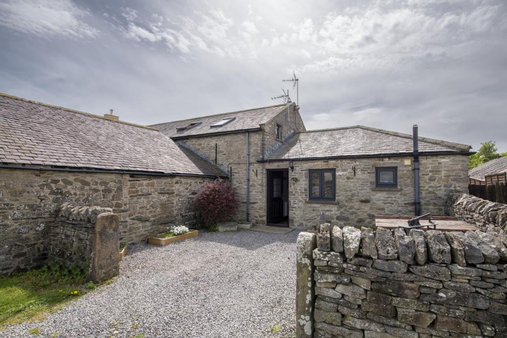 a stone house with a stone fence in front of it at Corner Cottage in Leyburn