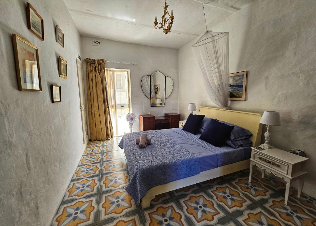 a bedroom with a blue bed and a mirror at Dar Garigor in Cospicua
