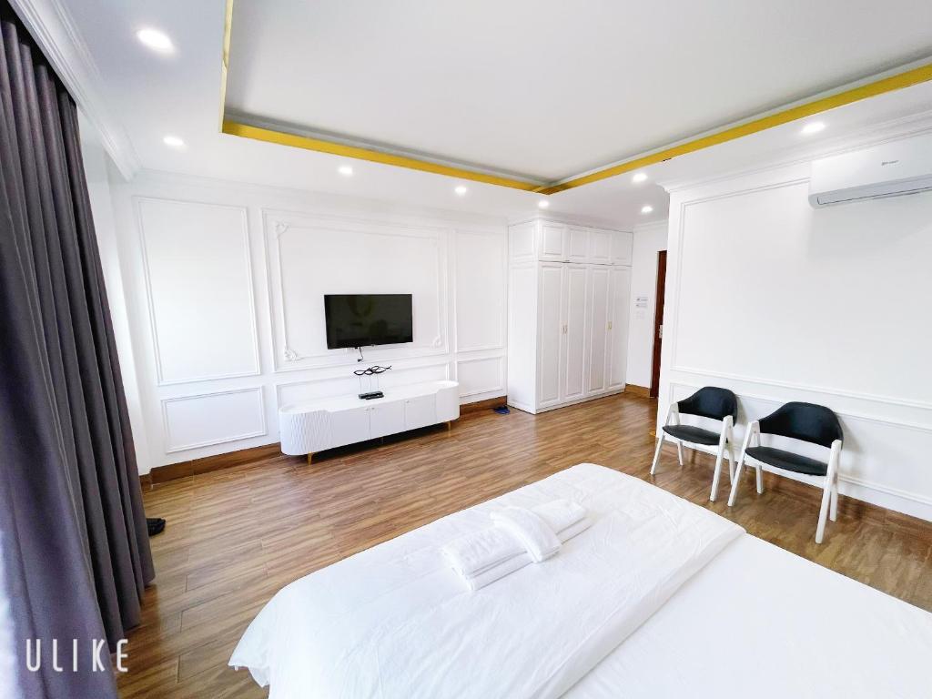 1 dormitorio blanco con 1 cama y 2 sillas en Minh Homestay, en Thôn Lại Thê