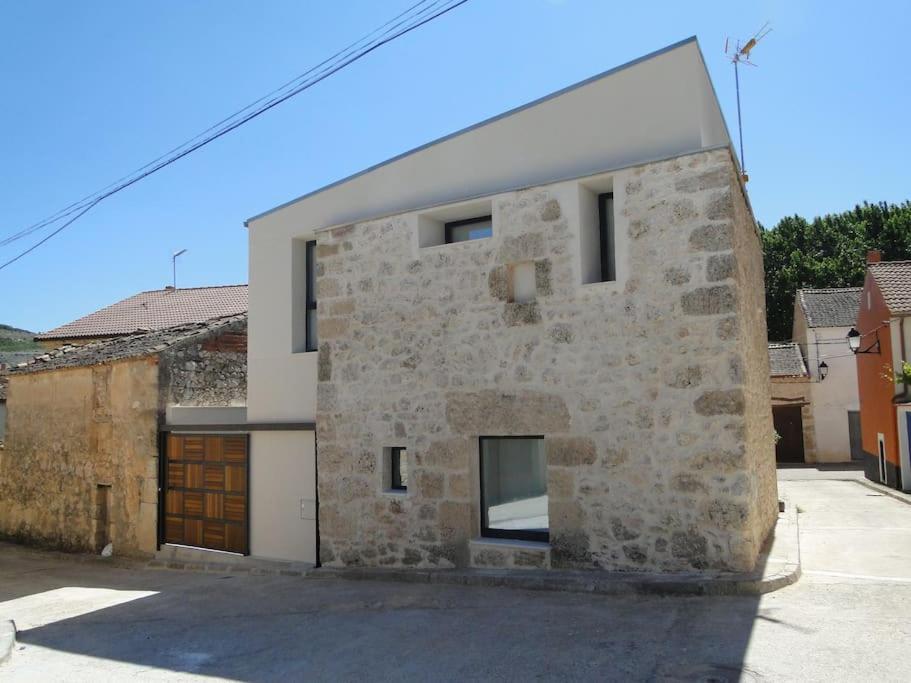 une maison en pierre avec une grande fenêtre latérale dans l'établissement LOS PUENTES casa con jacuzzi para 2, à Olmos de Peñafiel