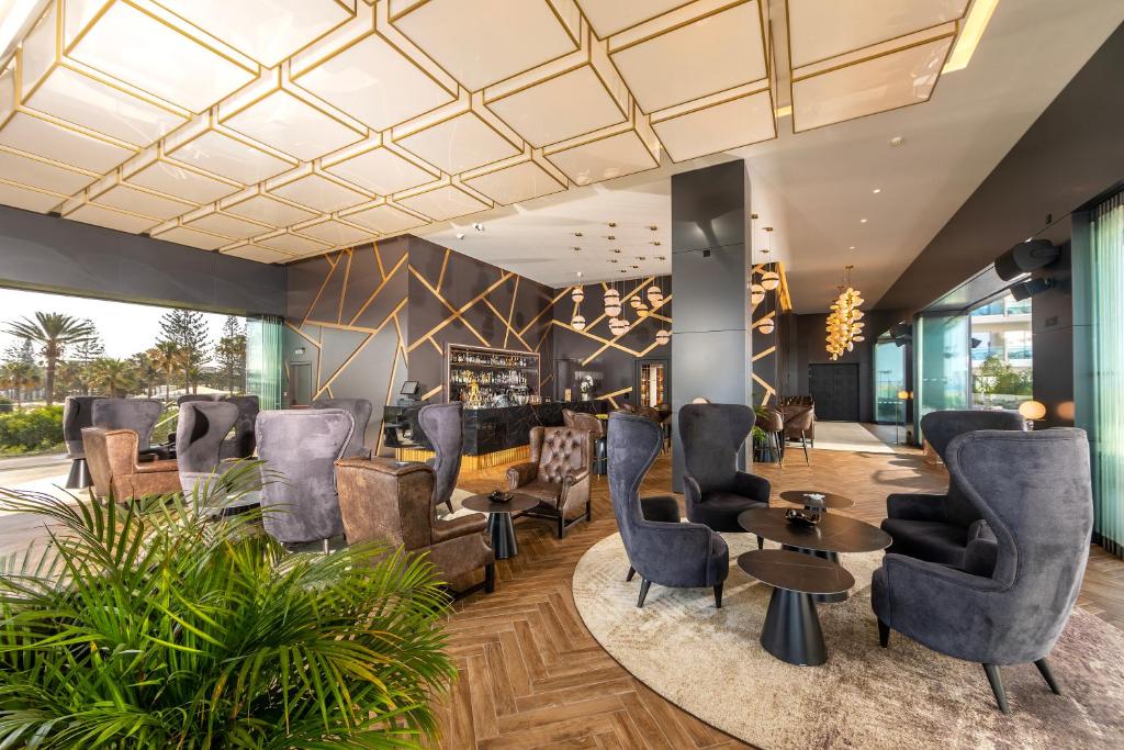 a lobby with chairs and tables in a salon at NissiBlu Beach Resort in Ayia Napa