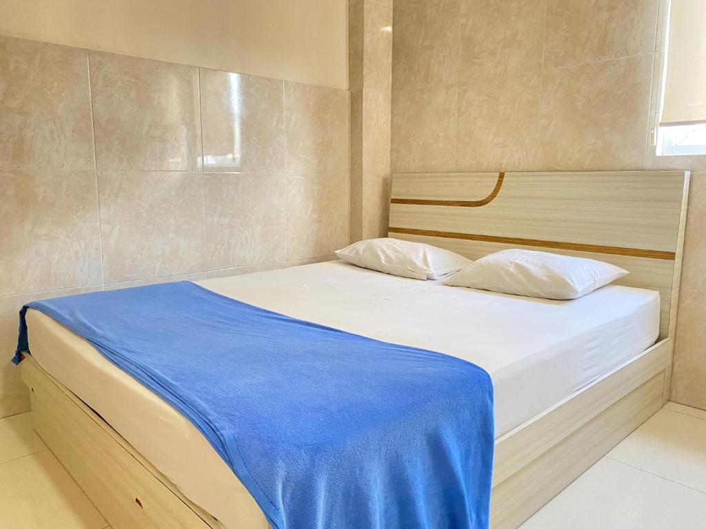 een slaapkamer met een bed met een blauwe deken erop bij Penginapan Star Ambon Mitra RedDoorz in Ambon