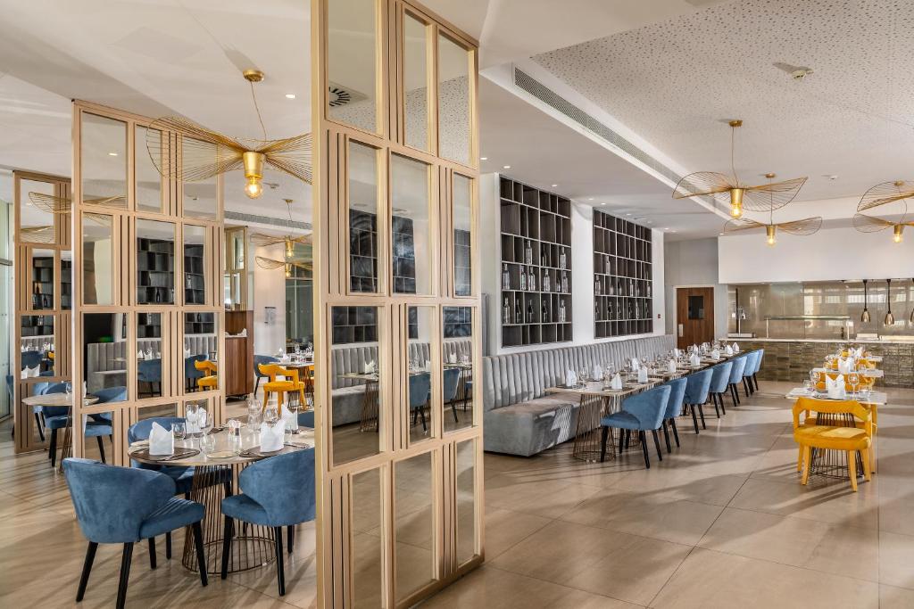 a dining room with tables and blue chairs at NissiBlu Beach Resort in Ayia Napa