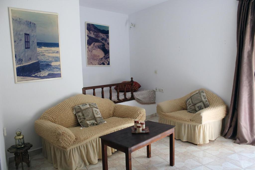 a living room with two chairs and a table at Volcano View Nisyros in Mandrákion