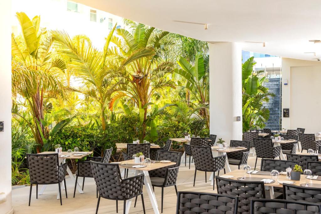 a restaurant with tables and chairs and palm trees at NissiBlu Beach Resort in Ayia Napa