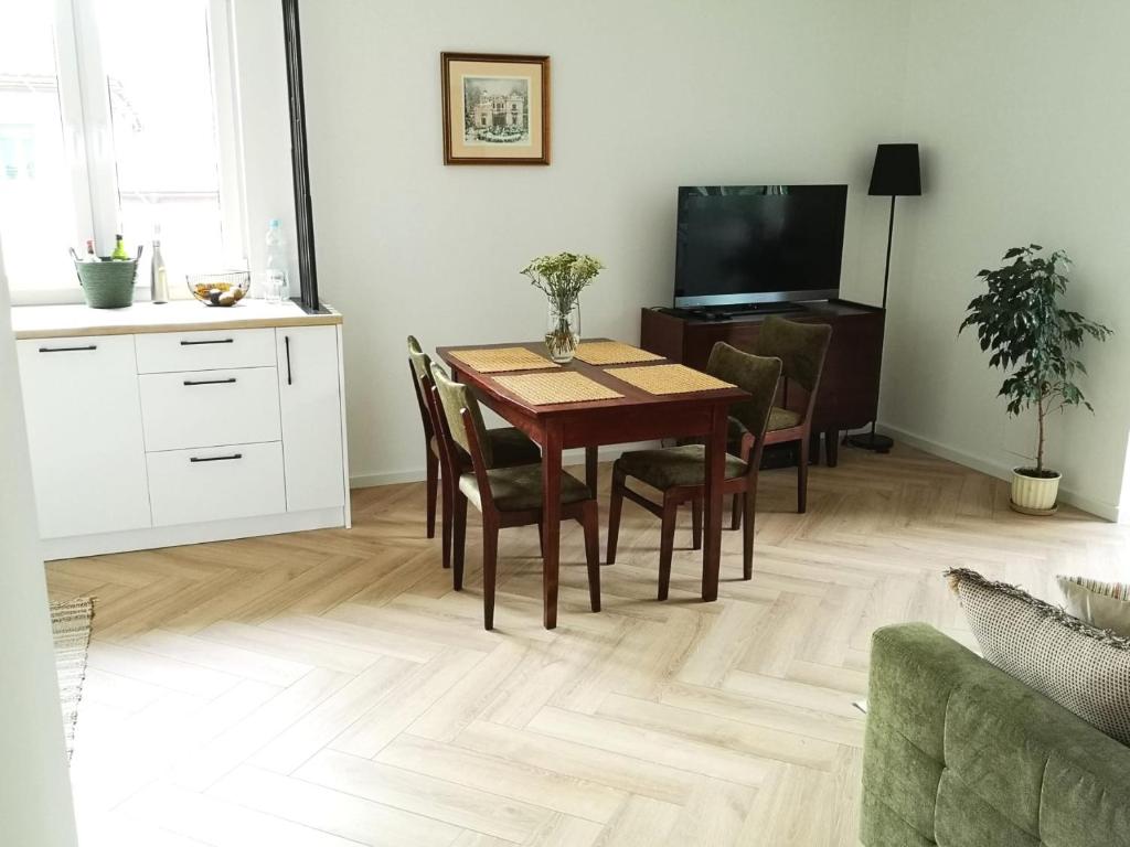 mesa de comedor con sillas y TV en Apartament Nałęczowski Zakątek, en Nałęczów