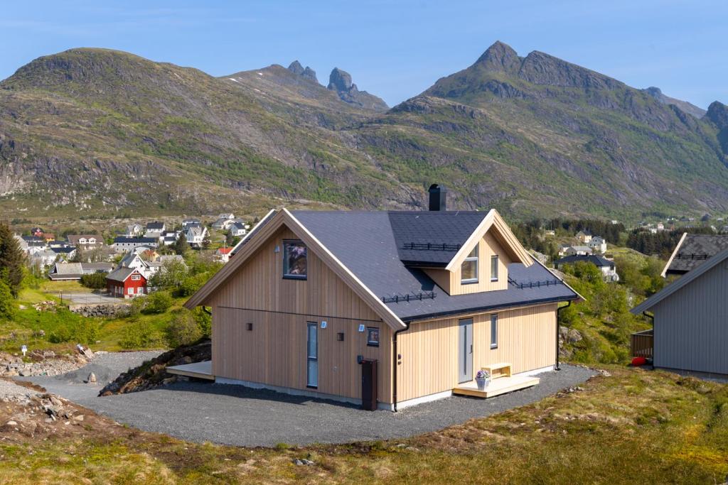 a house on a hill with mountains in the background at The Panorama - Sørvågen Lofoten in Sørvågen